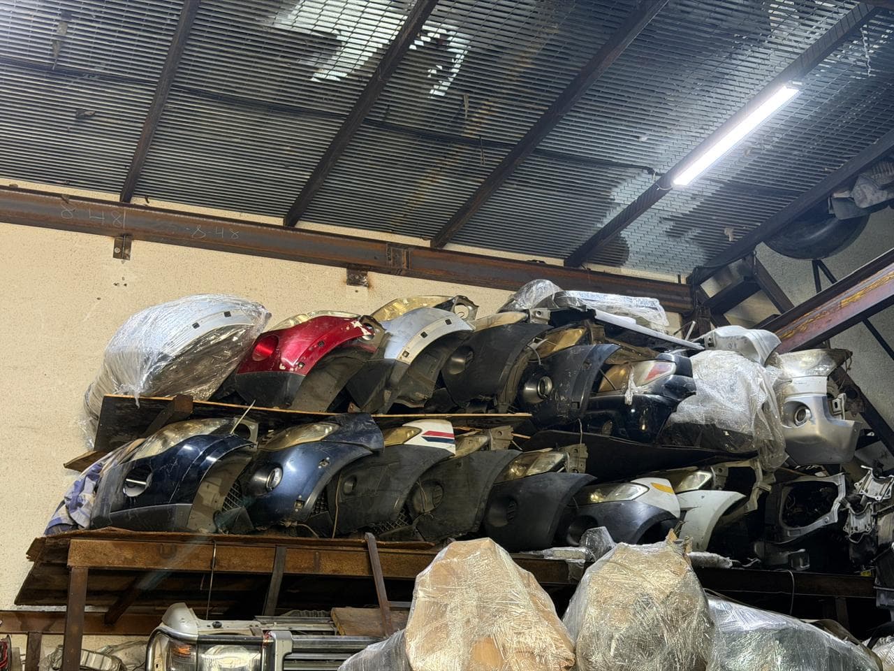 Used bumpers stacked on a rack at the shop